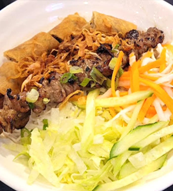 Grilled pork, crisp vegetables and spring rolls over vermicelli